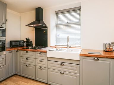 A kitchen with a gas stove microwave knife block sink and toaster at Coach House in Arnside