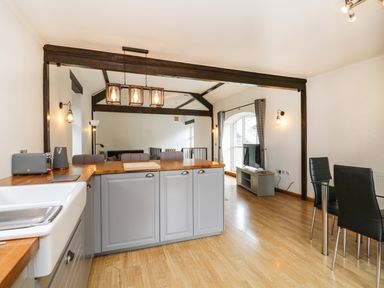 A kitchen and dining area with wooden floors and gray cabinets at Coach House in Arnside