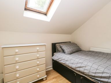 A bedroom with a single bed and a chest of drawers under a skylight window at Coach House in Arnside