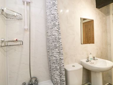 A bathroom with a shower and curtain toilet sink and mirror at Coach House in Arnside