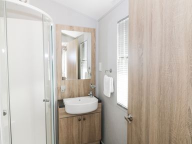 A bathroom with shower enclosure sink mirror towel on wall at Dershel Lodge in Southerness
