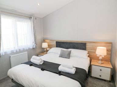 A bedroom with a double bed bedside tables and lamps at Dershel Lodge in Southerness