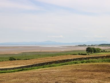 A rural landscape with fields stone wall trees and distant mountains at Dershel Lodge in Southerness