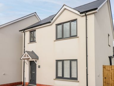 A two-story house with a gray front door and windows at LunaRoxx 6 Meadow Gardens Kilgetty