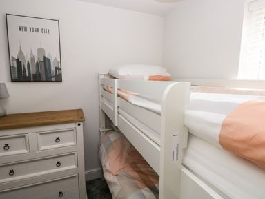 A bedroom with a white bunk bed a wooden dresser and a new york city poster on the wall at LunaRoxx 6 Meadow Gardens Kilgetty