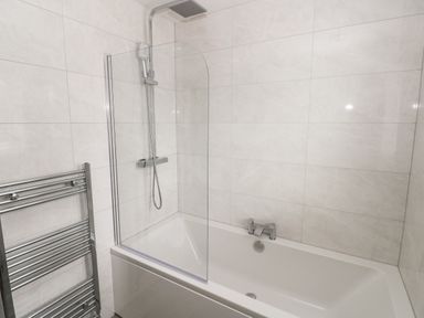 A bathroom with a bathtub shower combination and a towel radiator at LunaRoxx 6 Meadow Gardens Kilgetty