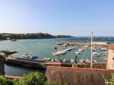 A coastal harbor with boats docked and a stone seawall at LunaRoxx 6 Meadow Gardens Kilgetty