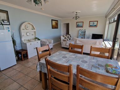 A dining area with wooden chairs and table with patterned tablecloth and a living room with armchairs and sofa in a room at High Tide in Duncannon County Wexford