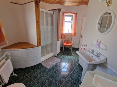 A bathroom with a shower enclosure a wicker chair a pedestal sink and a towel rack at High Tide in Duncannon County Wexford