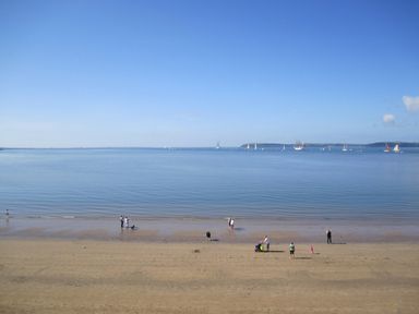 A beach with people near the water and sailboats on the sea at Beach House in Duncannon County Wexford