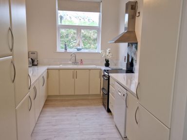 A kitchen with cream cabinets a window above the sink stove with hood dishwasher and kettle at Beach House in Duncannon County Wexford