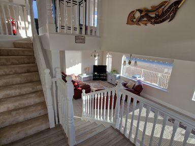 A living room with red sofas stairs and large window overlooking the beach at Beach House in Duncannon County Wexford