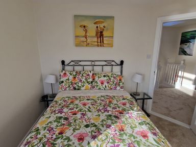 A bedroom with a bed with floral bedding and two bedside lamps at Beach House in Duncannon County Wexford