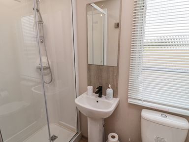 A bathroom with a shower enclosure sink with faucet and mirror toilet with window blinds at Plot 18 Meadow View in Felton
