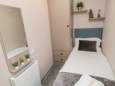 A small bedroom with a single bed a wardrobe a mirror and three small plants at Plot 18 Meadow View in Felton