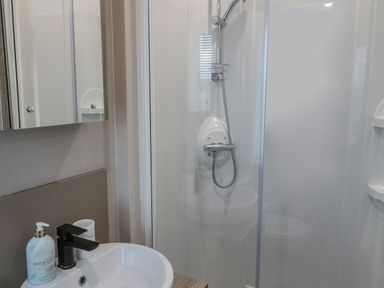 A bathroom with a shower enclosure and a sink with soap dispenser at Plot 18 Meadow View in Felton