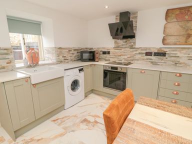 A kitchen with a washing machine oven microwave and a sink at Donni Hall Cottage in Beadnell
