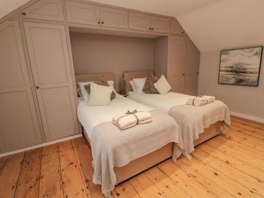 A bedroom with two single beds and built in closets at Donni Hall Cottage Beadnell