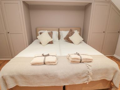 A bedroom with two single beds pushed together with pillows and folded blankets at Donni Hall Cottage in Beadnell