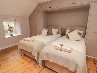 A bedroom with two single beds side by side with pillows and folded towels at Donni Hall Cottage in Beadnell