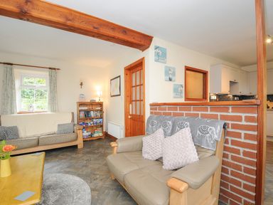 A living room with sofas a wooden coffee table a bookshelf and a partition wall at The Wagon House Lezant near Launceston