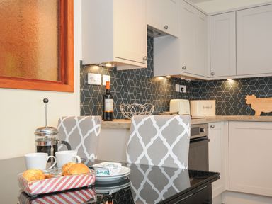 A kitchen with grey patterned chairs a black glass table scones cups and a coffee press The Wagon House Lezant near Launceston