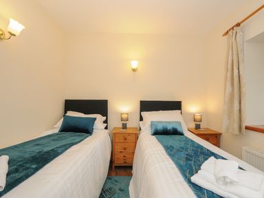 A bedroom with two single beds a wooden bedside table and lamps at The Wagon House Lezant near Launceston