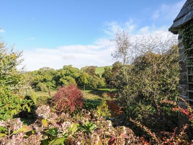 A garden with bushes and trees under a blue sky at The Wagon House in Lezant near Launceston