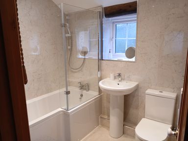 A bathroom with a bathtub shower combination pedestal sink and toilet at The Wagon House Lezant near Launceston
