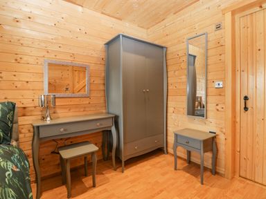 A wooden room with a desk lamp stool wardrobe two mirrors and a small table at The Lodge at Crossroads Farm in Middlezoy