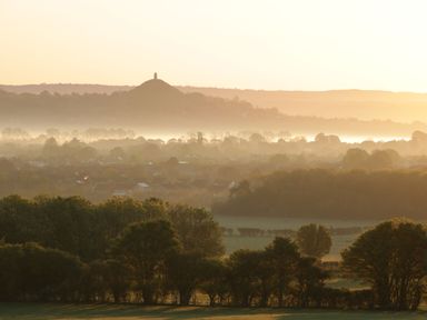 A landscape with trees fields and a hill with a tower in the background at The Lodge at Crossroads Farm in Middlezoy
