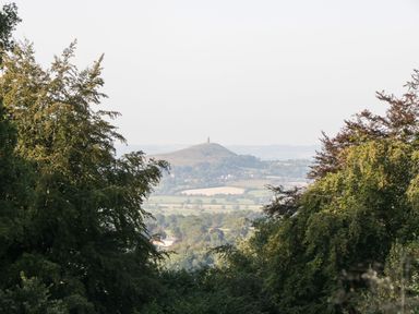 A hill with a tower in the distance surrounded by fields and trees at The Lodge at Crossroads Farm in Middlezoy