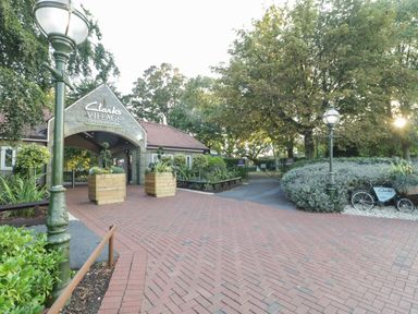 An entrance to Clarks Village outlet shopping with brick pavement lamp posts and plants at The Lodge at Crossroads Farm in Middlezoy
