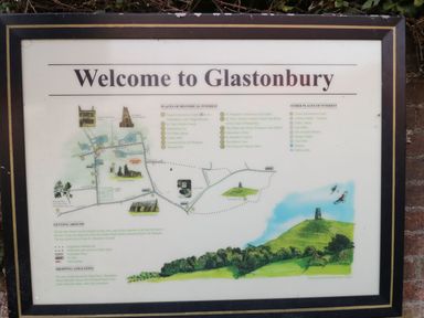 A framed informational welcome sign with a map and points of historical interest in Glastonbury