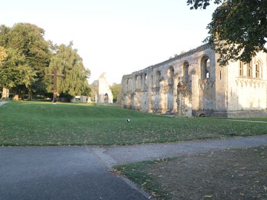 A stone building ruin with arches next to a grassy area with a wooden cross and trees at The Lodge at Crossroads Farm in Middlezoy