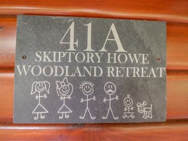A sign with number 41A Skiptery Howe Woodland Retreat with stick figure family and a dog at Woodland Retreat Skiptory Howe 41A White Cross Bay near Windermere