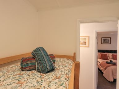 A bedroom with a wooden bed and animal patterned bedding with rolled colorful towels on top at Woodland Retreat Skiptory Howe 41A White Cross Bay near Windermere