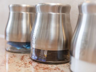 Three metal and glass containers labeled coffee on a countertop