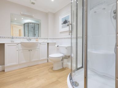 A bathroom with a sink cabinet toilet shower and a framed picture at Surf and Sand in Carbis Bay