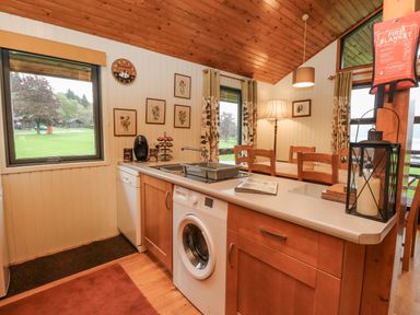 A kitchen and dining area with a washing machine coffee maker and wooden dining table at Firbush Lodge in Killin