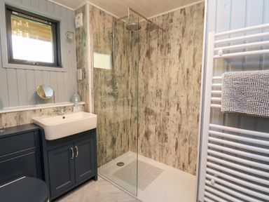 A bathroom with a walk in shower a sink with cabinet and a towel rail at Firbush Lodge in Killin