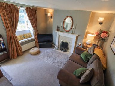 A living room with a sofa cushions and a fireplace at Lavender Cottage in Cark In Cartmel