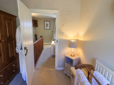 A hallway with a wooden railing and framed artwork on the wall at Lavender Cottage in Cark In Cartmel