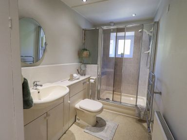 A bathroom with a sink toilet shower and round mirror at Lavender Cottage in Cark In Cartmel