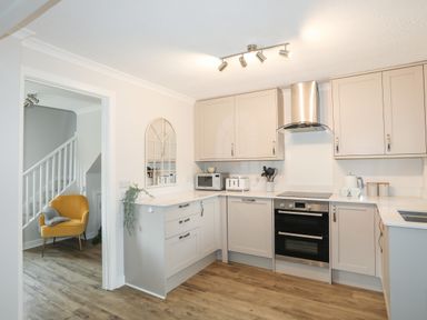 A kitchen with beige cabinets and appliances including an oven microwave and toaster at 240 Cae Du in Abersoch