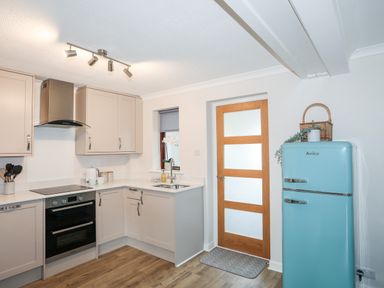 A kitchen with beige cabinets a stainless steel oven a blue refrigerator and a wooden door at 240 Cae Du in Abersoch