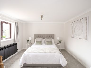 A bedroom with a bed bedside tables lamps and a framed spiral artwork at 240 Cae Du in Abersoch