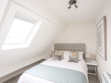 A bedroom with a bed pillows bedside tables lamps and a skylight window at 240 Cae Du Abersoch