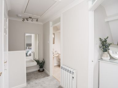 A hallway with a full-length mirror and potted plant next to a bathroom with a sink and toilet at 240 Cae Du in Abersoch