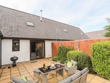 A patio with outdoor seating furniture and a barbecue grill at 240 Cae Du in Abersoch